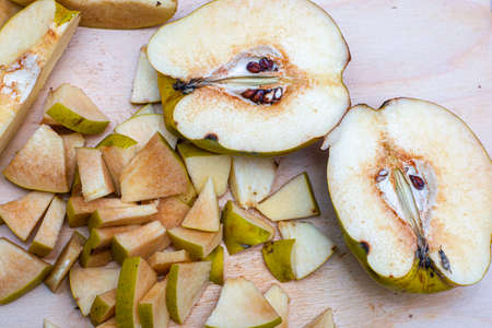the quince, sliced to make jam, lies on a wooden chopping board fotoの写真素材