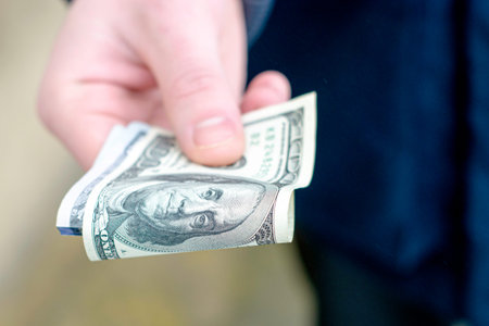 the hand holds out several hundred dollar bills folded in half. High quality photo