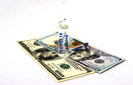 the concept of vaccination and business an ampoule with the inscription covid19 vaccine stands on banknotes on a white background. High quality photoの写真素材