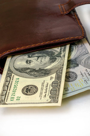 hundred-dollar bills sticking out of a leather purse. High quality photo