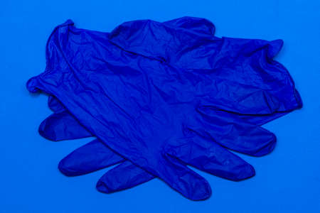 two blue medical gloves on a blue background folded into handshakes. High quality photoの写真素材