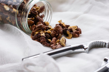 walnut kernels scattered from the jar lie on a napkin next to the nutcracker. High quality photo
