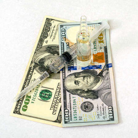 the concept medicine and business the syringe and ampoule with the medicine are on hundred dollar bills. High quality photoの写真素材