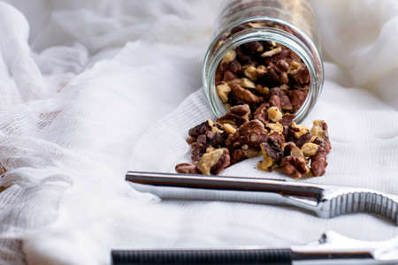 walnut kernels scattered from the jar lie on a napkin next to the nutcracker. High quality photoの写真素材