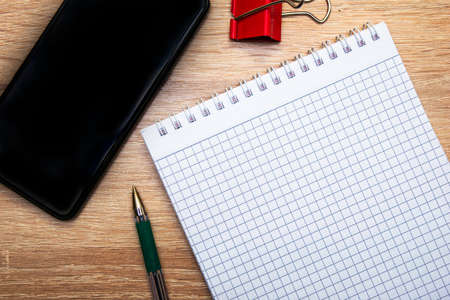 a notepad a fountain pen a smartphone and a stationery clip are on the copy space desk. High quality photoの写真素材