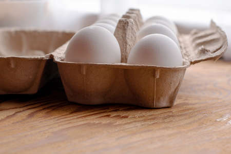 white chicken eggs in a paper tray stand on the table close up. High quality photoの写真素材