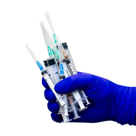 a hand in a blue medical glove holds a lot of syringes on the white background. High quality photo