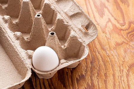 one white chicken egg is in a package on the table. High quality photo