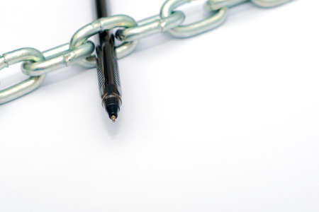 a fountain pen stuck in a chain on sheets of white paper a concept of freedom of speechの写真素材