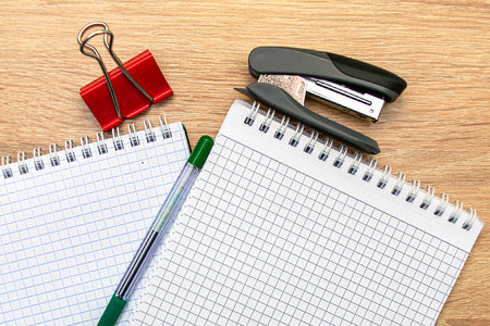 two notepads a paper clip a stapler and a fountain pen are on the table. High quality photo