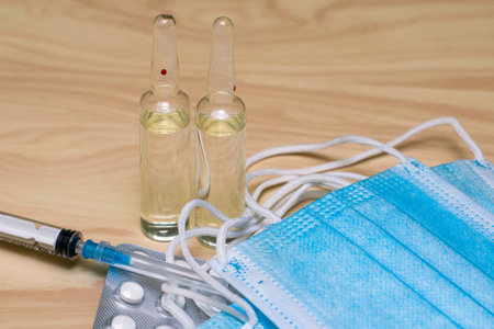 a syringe tablets in blisters medical hygiene masks and ampoules with medicines on the table. High...
