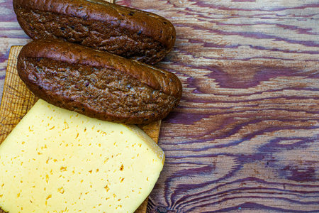 a piece of cheese and two loafs of rye bread on the cutting board copy spaceの写真素材