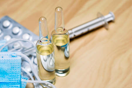 a syringe tablets in blisters medical hygiene masks and ampoules with medicines on the table. High quality photoの写真素材