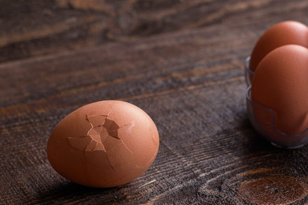 tray with eggs on a wooden table one egg is chipped and lies separately. High quality photoの写真素材
