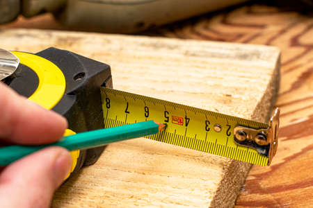 the carpenter marks the distance to measure with a pencil on a tape measure. High quality photoの写真素材