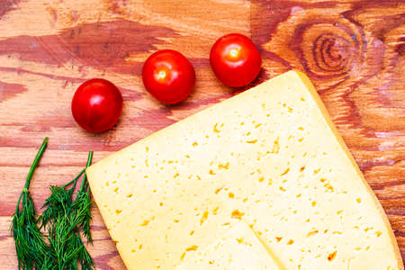 cheese greens and cherry tomatoes on a cutting board on the table. High quality photoの写真素材