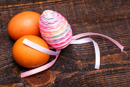 three chicken eggs on a wooden surface one egg is decorated with an Easter ribbon. High quality photoの写真素材