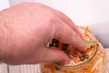 a man puts cabbage in a glass jar for salting with his hands. High quality photoの写真素材