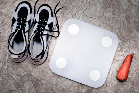 scales sneakers and carrots on the floor concept diet proper nutrition sports. High quality photoの写真素材