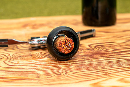 a wine stopper with a corkscrew on a wooden table in the background a bottle of wine. High quality photoの写真素材