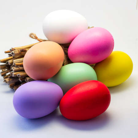 colorful Easter eggs and a bundle of firewood on a light background happy Easter concept. High quality photoの写真素材