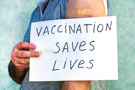 a man with a vaccine patch on the river holds a sign that reads vaccination seven lives vaccination...