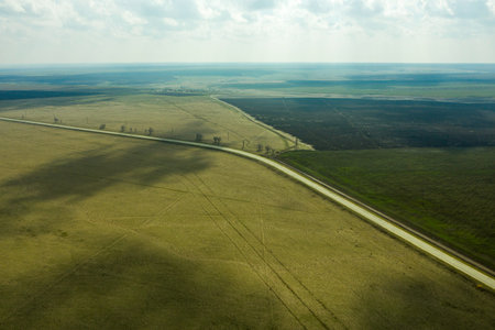 a wedge of arable land among fields and a highway spring landscape shooting from a drone. High...