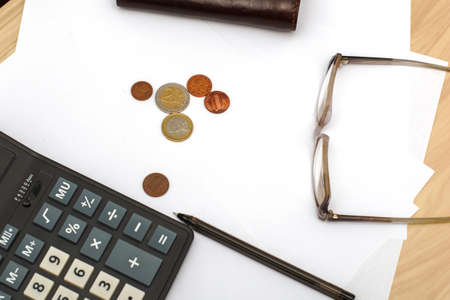 wallet calculator glasses fountain pen and small coins on white sheets of paper on the table concept budget economy finance. High quality photoの写真素材
