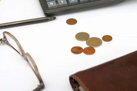 wallet calculator glasses fountain pen and small coins on white sheets of paper on the table concept budget economy finance. High quality photoの写真素材