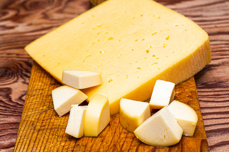 one large and several small pieces of cheese on a cutting board. High quality photo