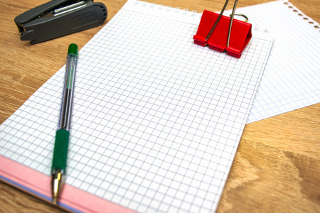 two open notepads a fountain pen a stapler and a stationery clip on the table. High quality photo