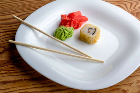 baked sushi with eel wasabi ginger and chopsticks on a white plate. High quality photoの写真素材