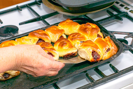 a woman with a metal spatula removes freshly baked rosy pies from a baking sheet. High quality photo