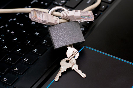 internet cable passing through a closed iron lock with keys on a laptop keyboard data protection...