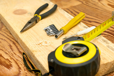 measuring tape pliers pencil screwdrivers and a board on the carpenter's workbench. High quality...