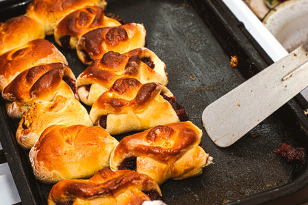 a woman with a metal spatula removes freshly baked rosy pies from a baking sheet. High quality photo