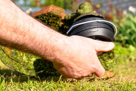 a man winds a new bobbin on a mowing trimmer. High quality photoの写真素材