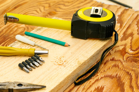 measuring tape pliers pencil screwdrivers and a board on the carpenter's workbench. High quality photoの写真素材
