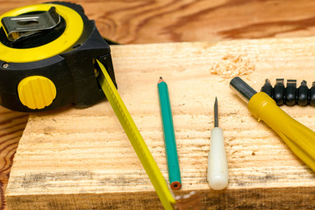 measuring tape pencil screwdrivers and a board on the carpenter's workbench. High quality photoの写真素材