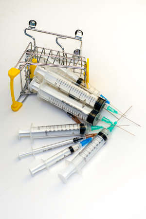 overturned shopping cart with syringes on a white background concept medicine pharmacy vaccinationの写真素材