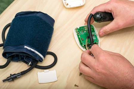 the master repairs the electronic tonometer inserts a rubber bulb into the body of the tonometerの写真素材