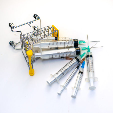 overturned shopping cart with syringes on a white background concept medicine pharmacy vaccination....