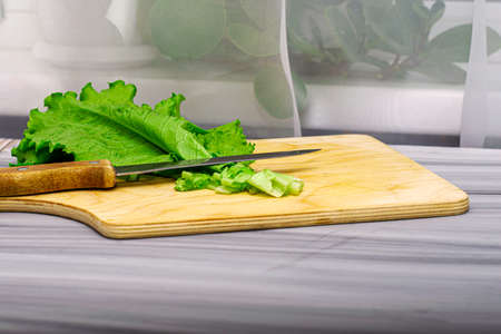lettuce leaves on a cutting board next to a knife on the table. High quality photoの写真素材
