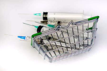 an overturned shopping basket full of medical syringes of various volumes concept vaccination pharmaceuticals. High quality photoの写真素材