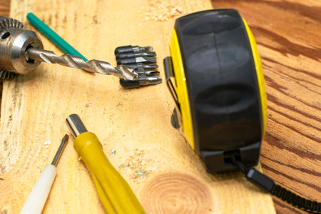 measuring tape measure drill with a drill pencil screwdrivers board on a wooden workbench. High...