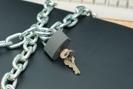 the laptop is wrapped with an iron chain and closed with a padlock with keys the concept of...