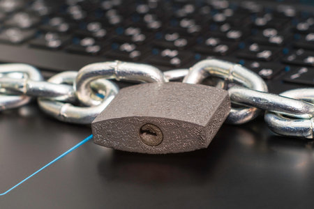 an iron chain fastened with a padlock on a computer keyboard the concept of data protection...