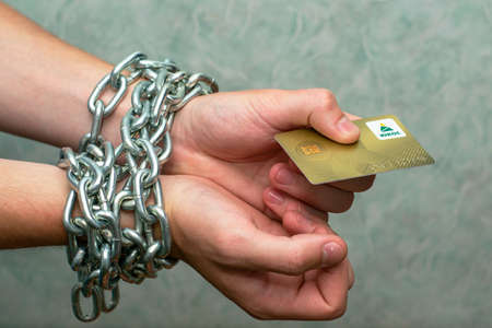 07/29/2021 Divnoye Stavropol Territory Russia the golden refueling card of the YUKOS company in the hands of a man chained in an iron chain the concept of business raiding oil fuel. High quality photoのeditorial素材