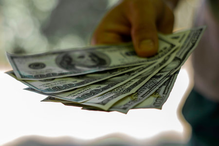 a man holds a stack of hundred-dollar bills in his hand. High quality photo