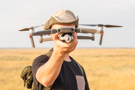 a tourist guy launches a quadcopter and holds it in his hand. High quality photoの写真素材